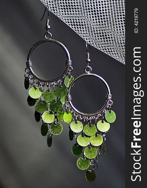 A pair of green earrings hanging on a web. A pair of green earrings hanging on a web