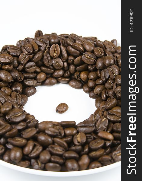 Coffee beans in a circle on a white saucer