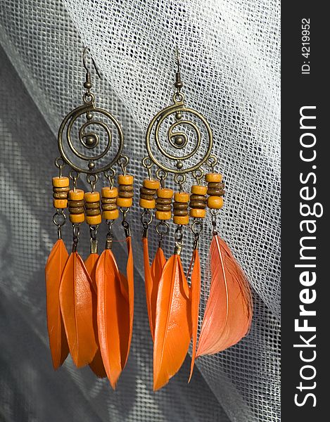 A pair of orange earrings with feather