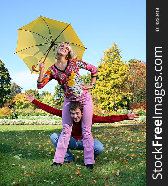 Young beautiful couple have fun under yellow umbrella. Young beautiful couple have fun under yellow umbrella