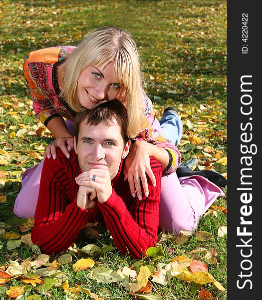 Young beautiful couple is laying on the autumn grass