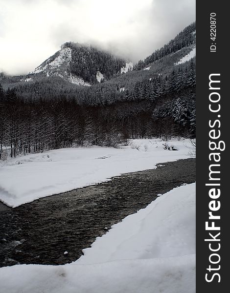 A stream flowing through snow covered mountains. A stream flowing through snow covered mountains.