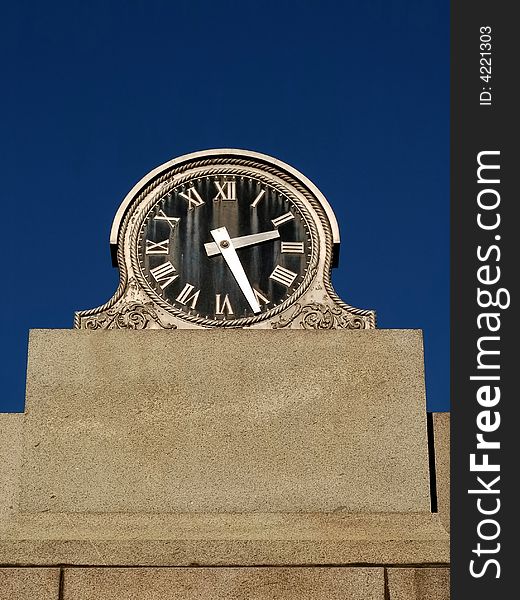 Old black faced clock with blue sky