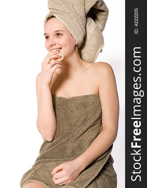 Young woman in towel on a white background eating. Young woman in towel on a white background eating