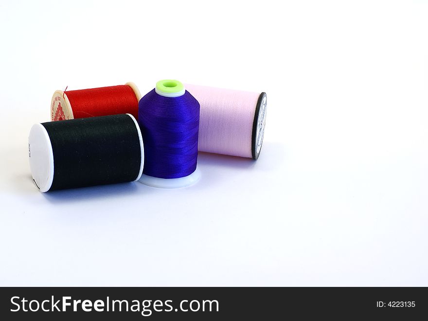 Four spools of thread on white background.