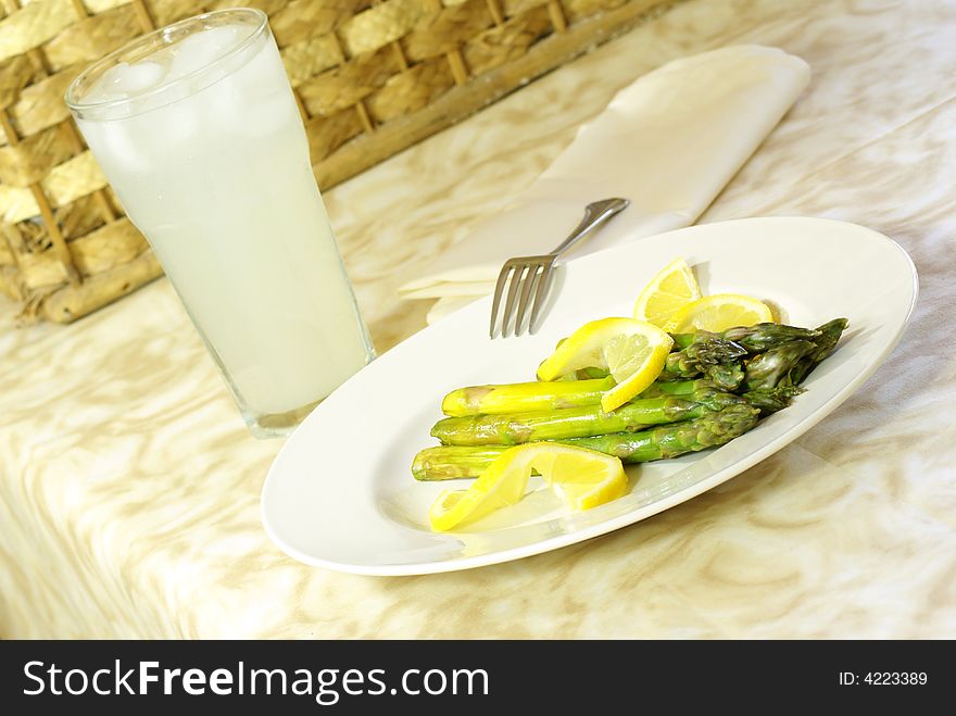 Asparagus stalks on white plate with lemon twists.