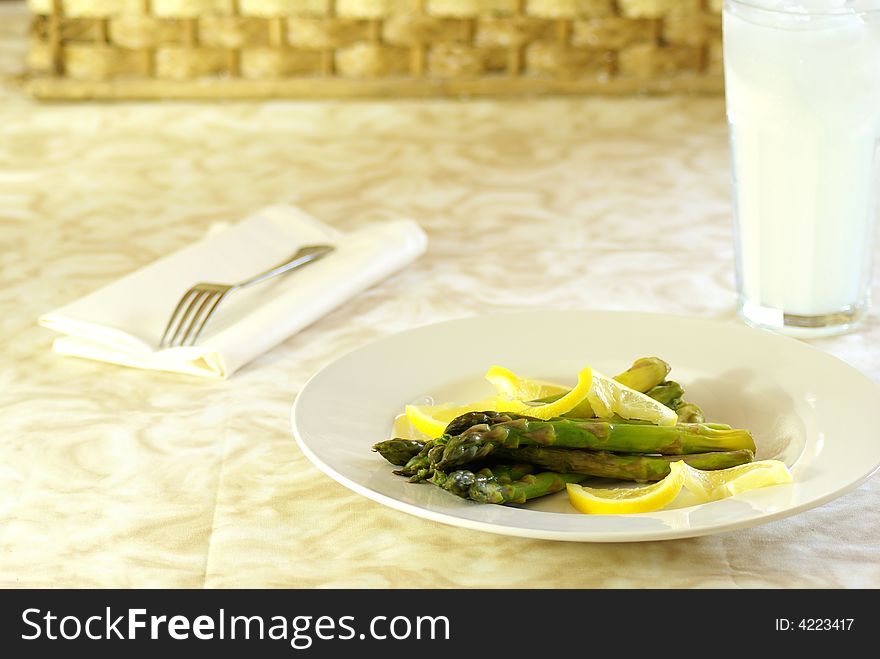 Asparagus stalks on white plate with lemon twists.