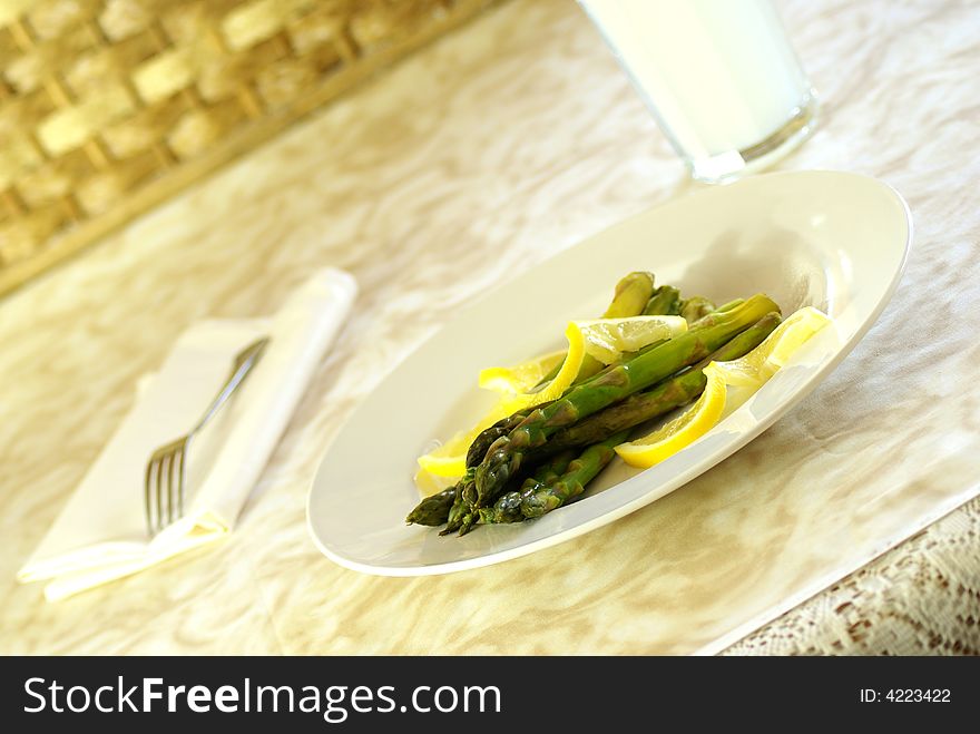 Asparagus stalks on white plate with lemon twists.