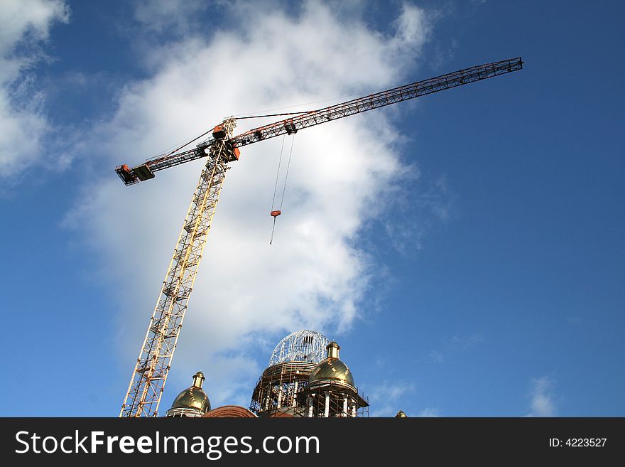 Tall crane and construction in cloudy blue sky