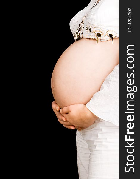 A pregnant lady holding her tummy with a black background