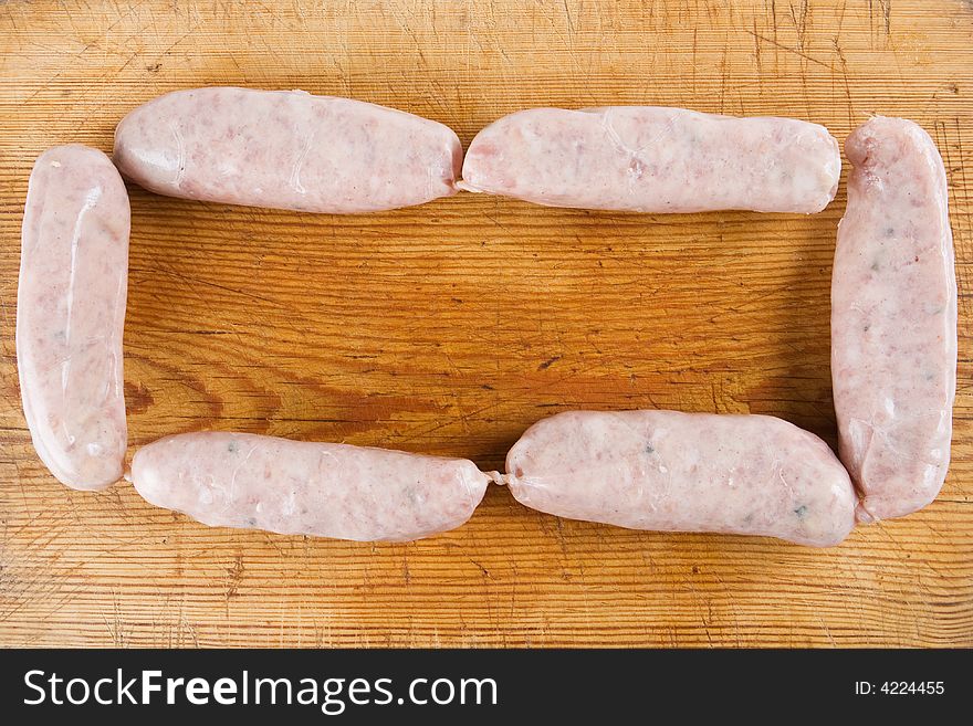 Six uncooked sausages on a wooden background