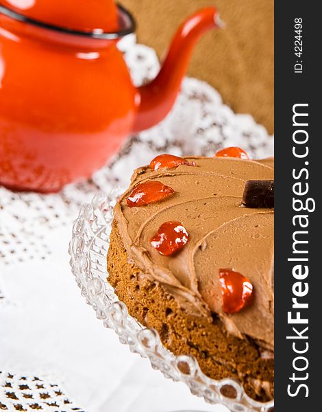 Freshly baked chocolate cake with a red tea pot in the background