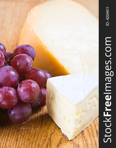 Gouda, camembert and grapes on a wooden board