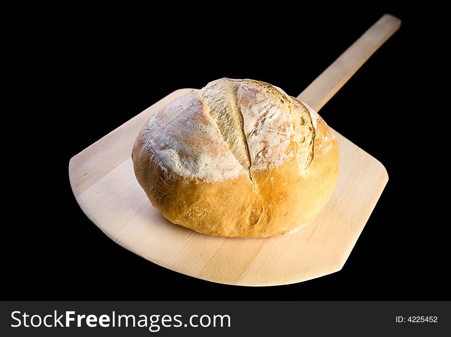 Delicious rustic  fresh Italian bread on a baking peel, black background. Delicious rustic  fresh Italian bread on a baking peel, black background