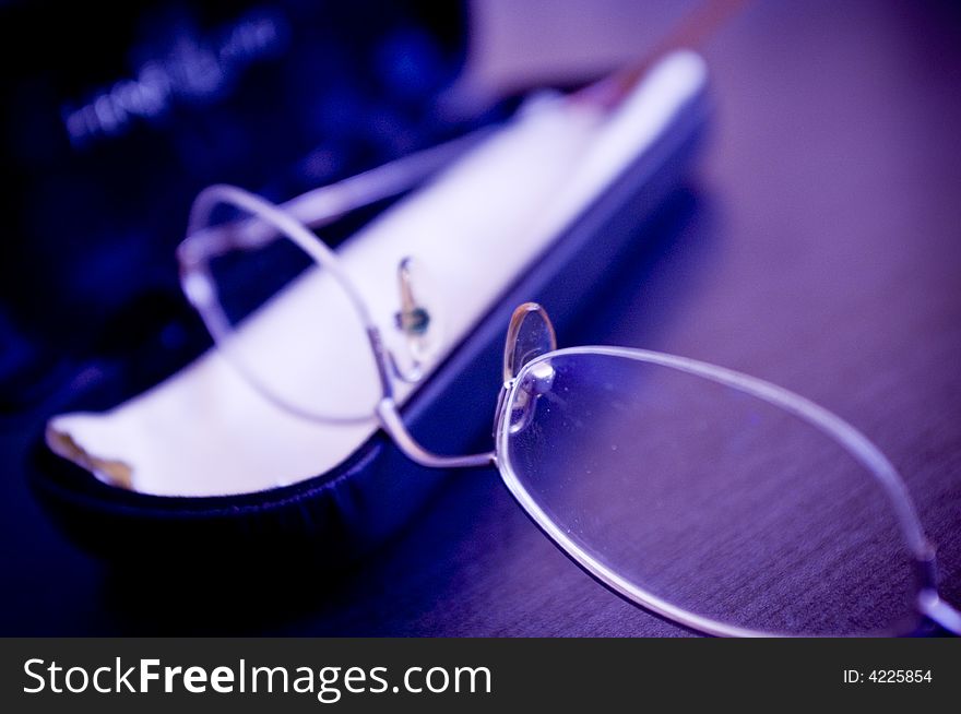 A closeup view of eyeglasses laying on a table or desk.  Color modified. A closeup view of eyeglasses laying on a table or desk.  Color modified