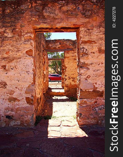 Kanyaka Ruins near Hawker featuring several doorways in a ruined outback building, looking through to a modern coupe car (Flinders Ranges, South Australia).