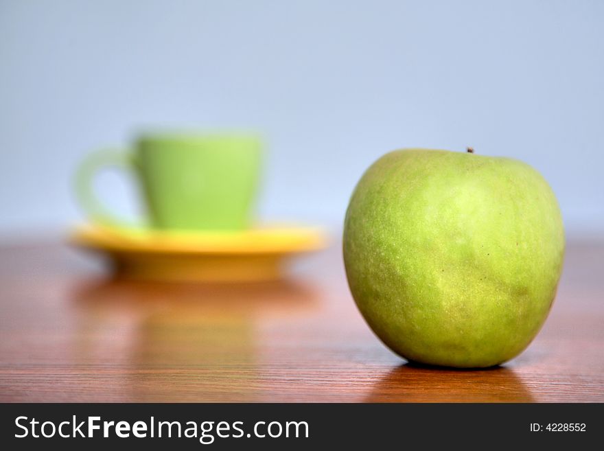 An image of  green teacup and green apple. An image of  green teacup and green apple
