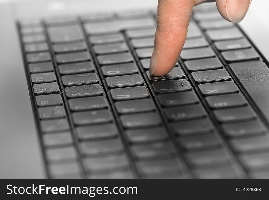 Close up of a black keyboard with a person's hand typing on it. One finger. Close up of a black keyboard with a person's hand typing on it. One finger