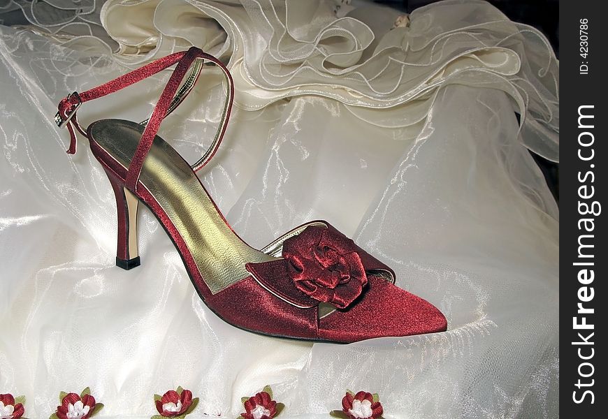 Red satin shoes over folded dress of bride. Red satin shoes over folded dress of bride
