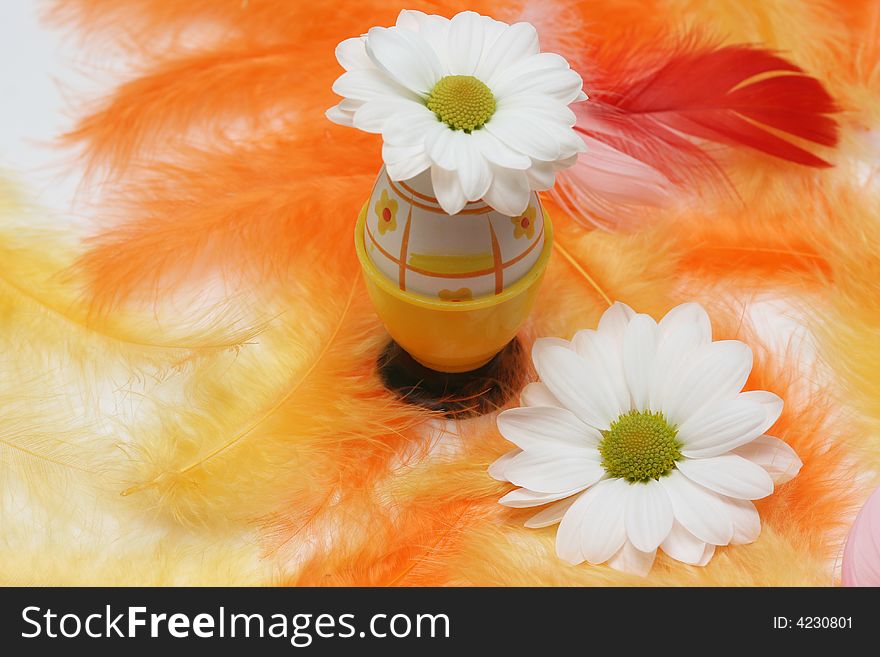 Easter egg with flower on yellow and orange feathers.