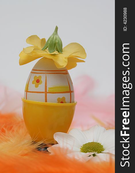 Easter egg with flower on yellow and orange feathers.