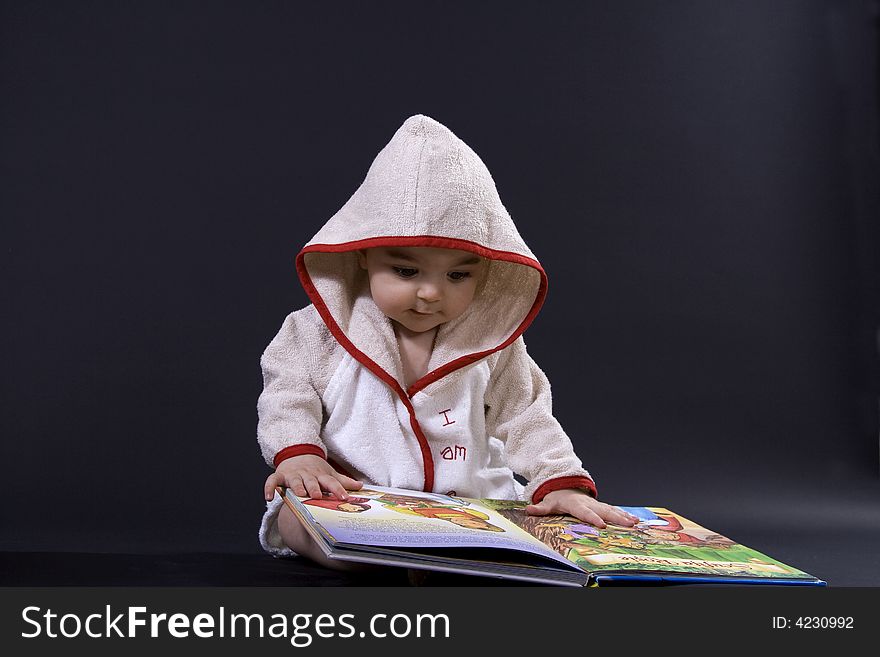 Curious happy baby on black surface reading a story. Curious happy baby on black surface reading a story