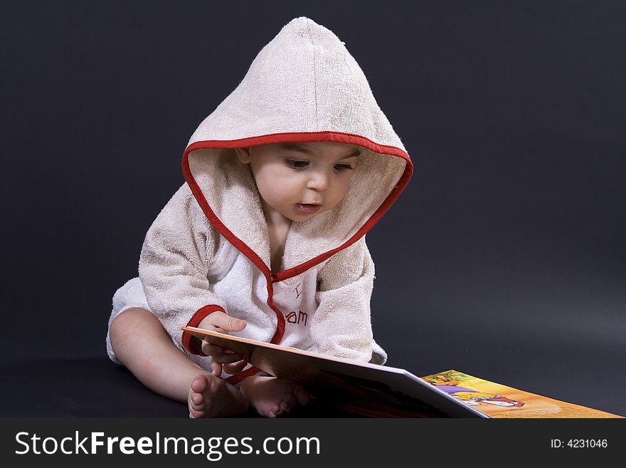 Curious happy baby on black surface reading a story. Curious happy baby on black surface reading a story