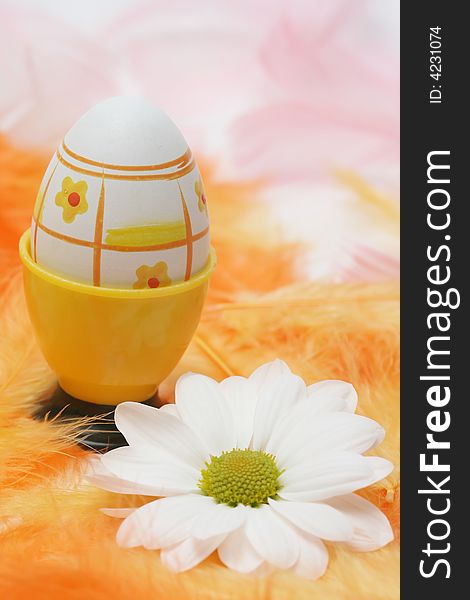 Easter egg with white flowers and pink and orange feathers.