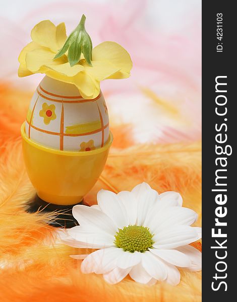 Easter egg with flowers and pink and orange feathers.