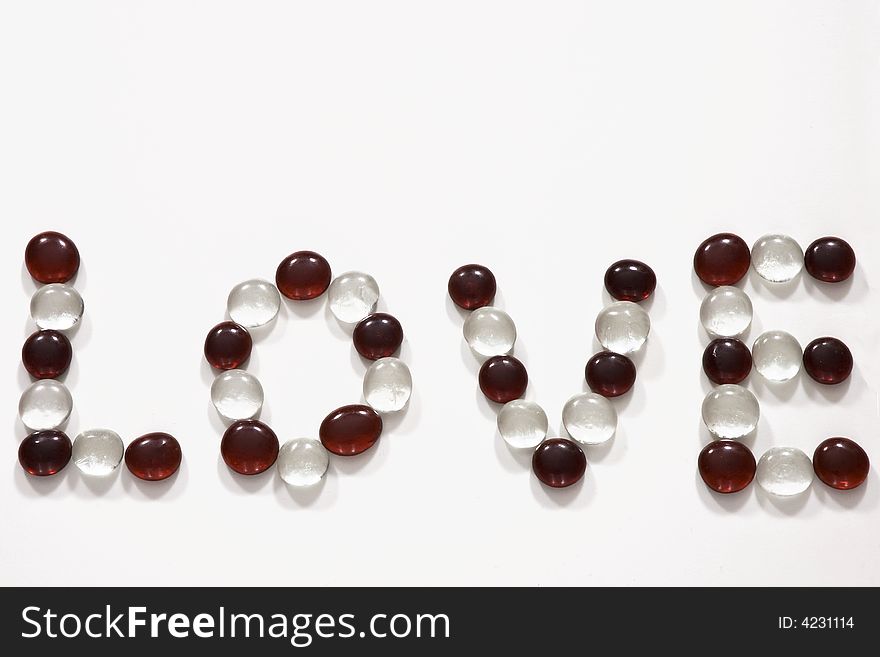 Table jewels aranged to spell out the work love in red and clear on a white background