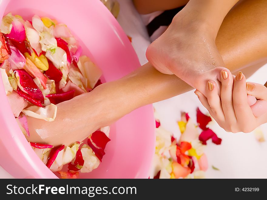 Beautiful young woman legs in water with petals. Beautiful young woman legs in water with petals