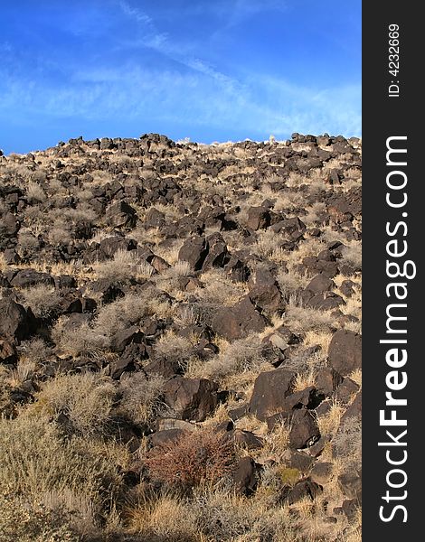 A rocky hill leading into a cloudy blue sky