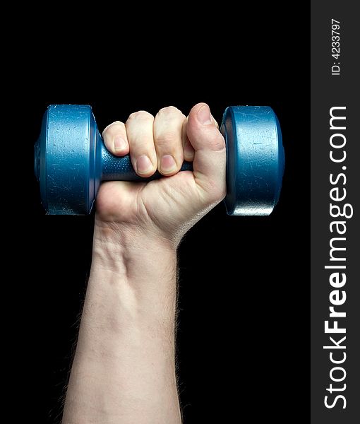 Dumbbell in a hand on a black background.