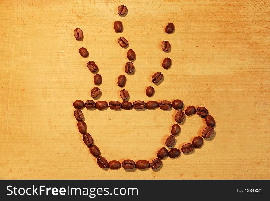 Cup of hot flavoured coffee spreaded out of coffee beans