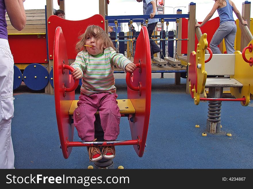 Toddler girl happily playing on seesaw. Toddler girl happily playing on seesaw.