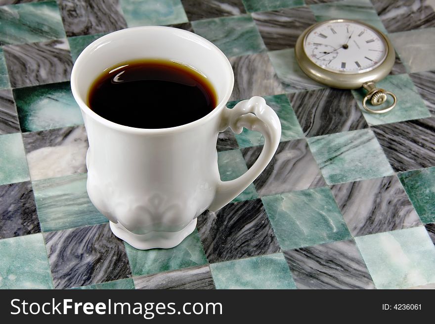 Cup of coffee with an antique pocket watch in the background. Cup of coffee with an antique pocket watch in the background.