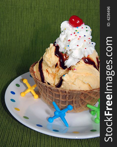 Hot fudge sundae in a waffle bowl with toy jacks. Hot fudge sundae in a waffle bowl with toy jacks.