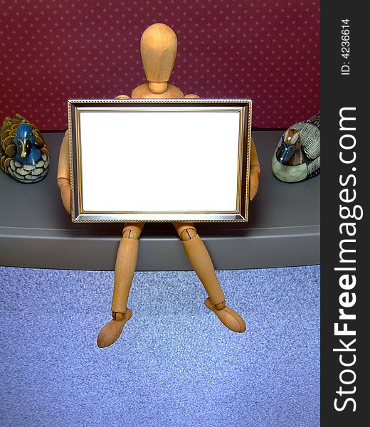 An artist's manikin holding a small picture frame that is blank for text or similar - sitting on a TV set. An artist's manikin holding a small picture frame that is blank for text or similar - sitting on a TV set.