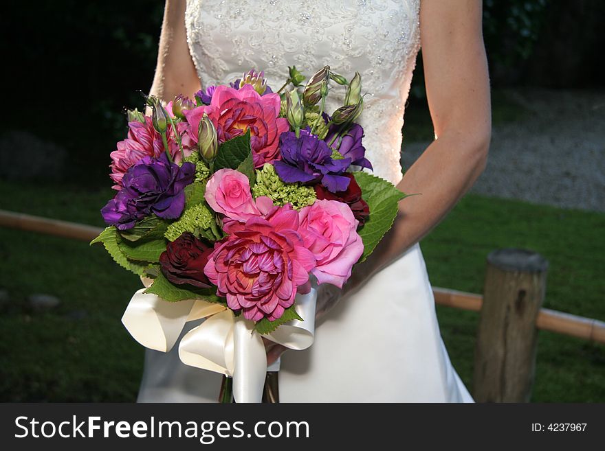 Bride holds her bouquet of pinks and greens. Focus on flowers. Bride holds her bouquet of pinks and greens. Focus on flowers.