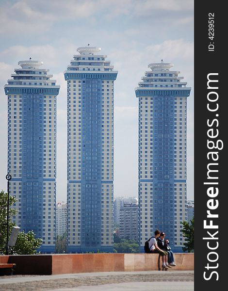 Two people sitting in front of three skyscrapers