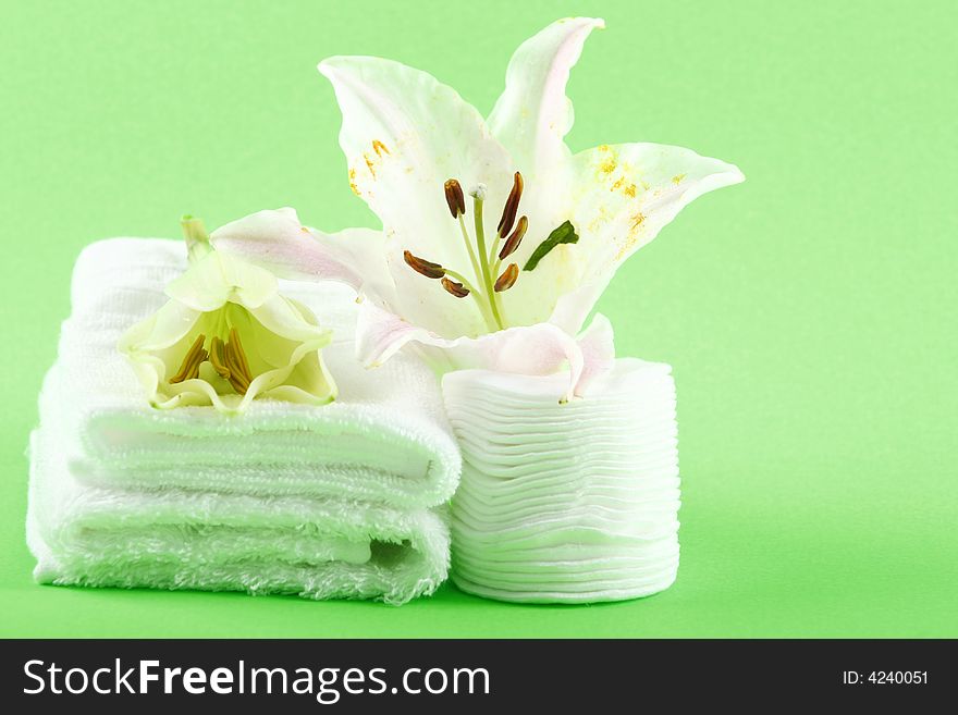 white towels and fresh lily on green color background