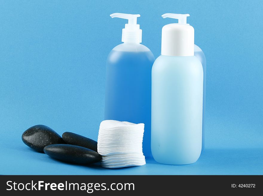 Three zen stones on blue  color background with cosmetics