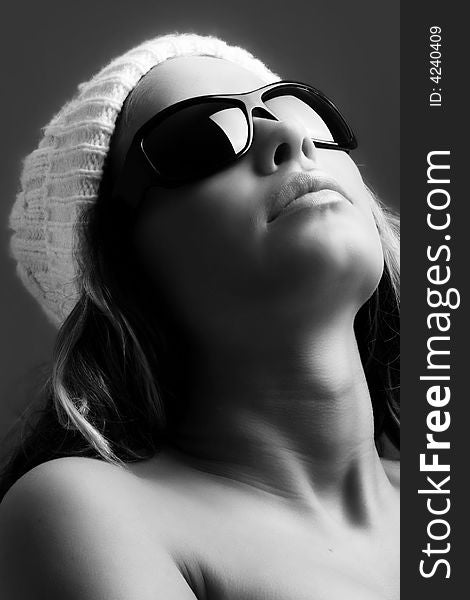 Portrait of a beautiful woman with a cap and some sunglasses against grey background. Portrait of a beautiful woman with a cap and some sunglasses against grey background