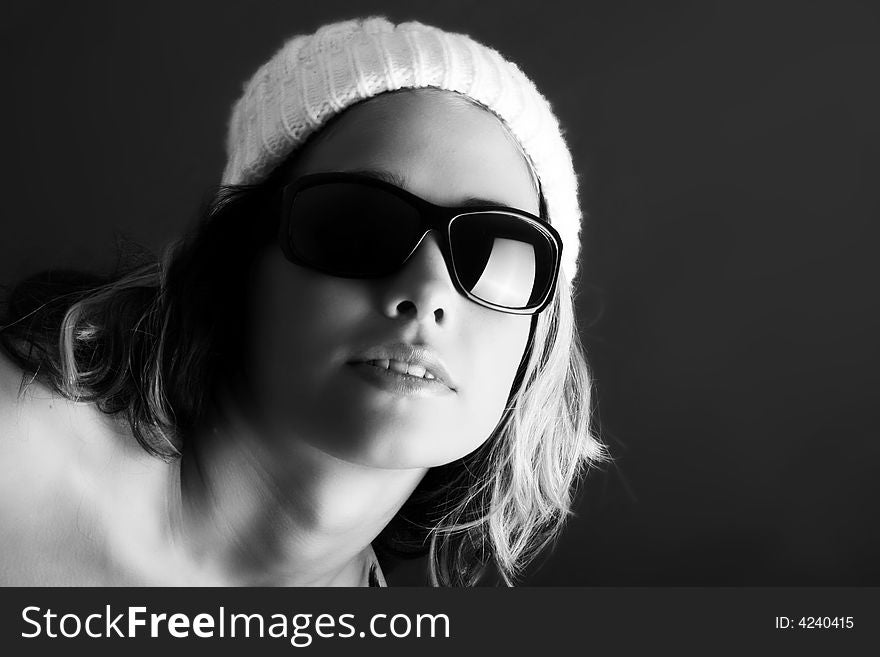 Portrait of a beautiful woman with a cap and some sunglasses against grey background. Portrait of a beautiful woman with a cap and some sunglasses against grey background