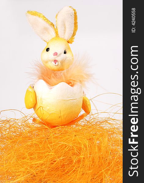 Easter bunny toy at orange hay on white background. Easter bunny toy at orange hay on white background