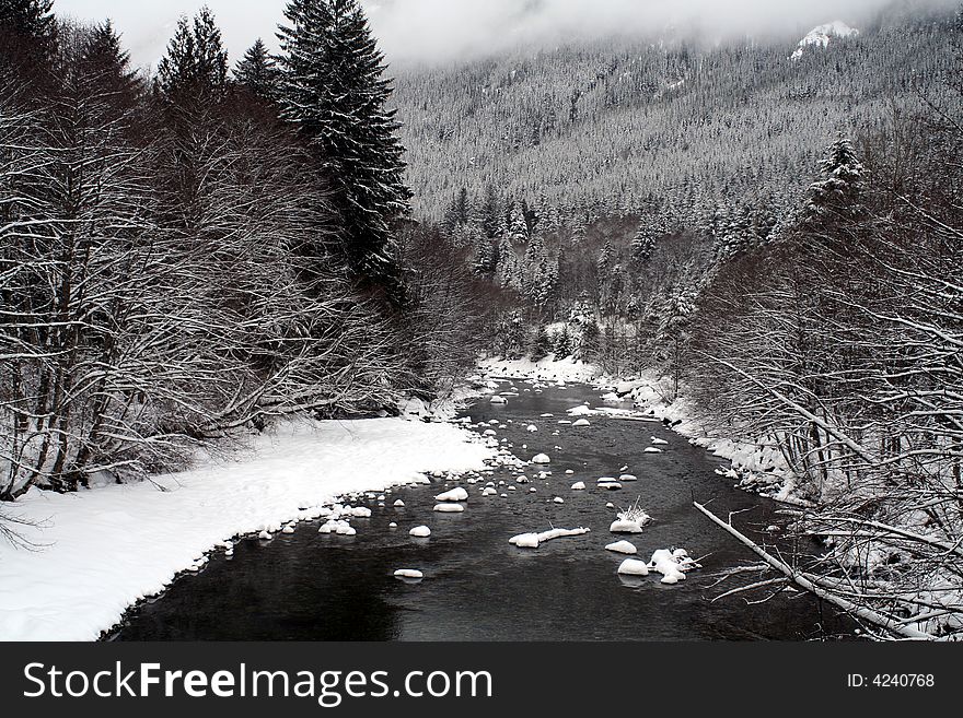 A stream flowing through snow covered mountains. A stream flowing through snow covered mountains.