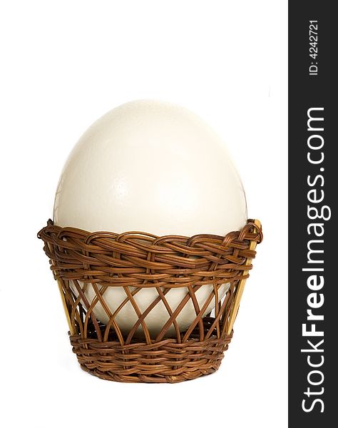 Ostrich egg in a wicker basket on white background
