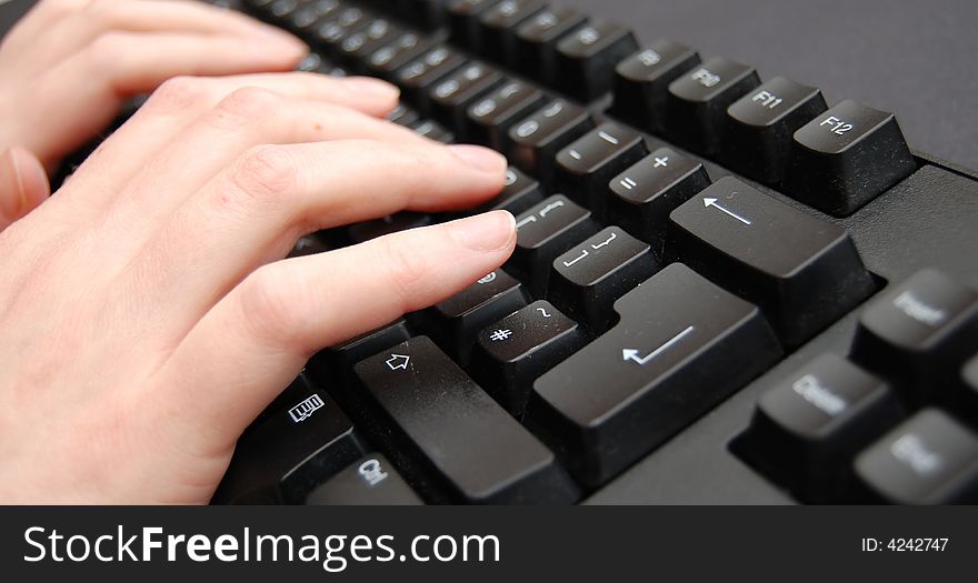 Pair of hands typing on a black keyboard. Pair of hands typing on a black keyboard