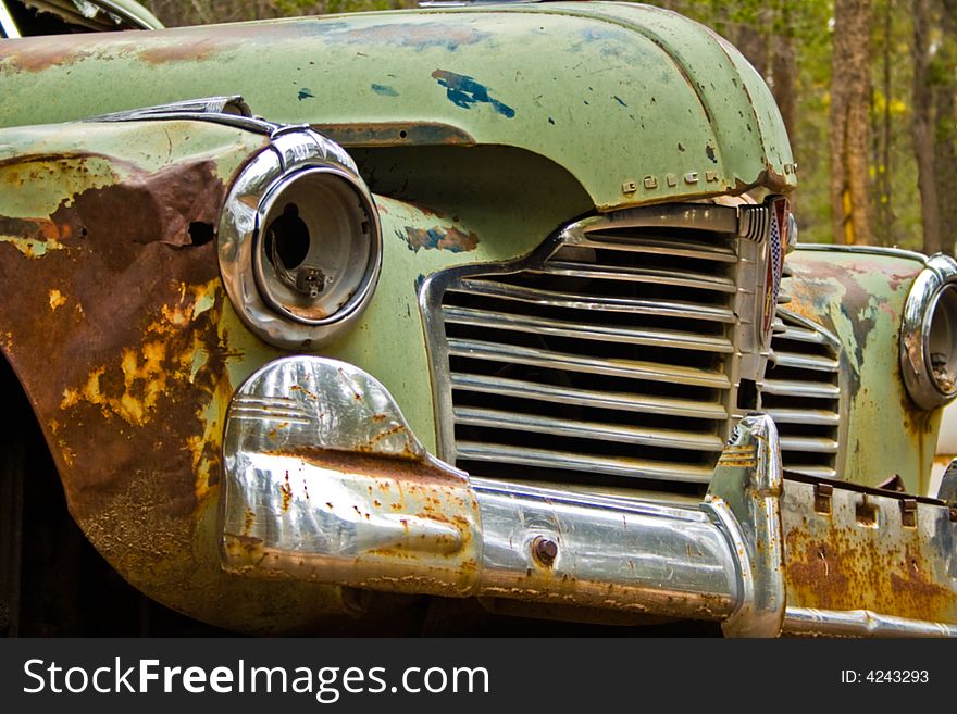 The front view of a green Buick  hardtop abandoned in the woods. The front view of a green Buick  hardtop abandoned in the woods