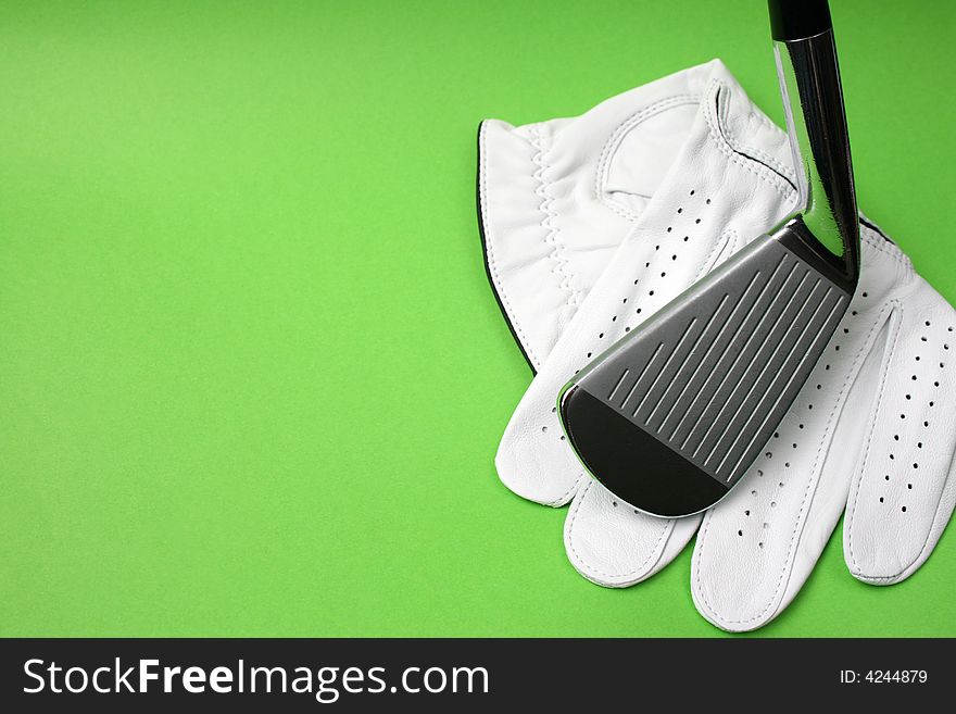 Golf glove and club on a green background